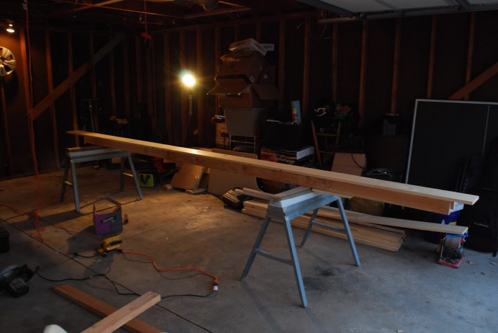 Two sawhorsers with a long pine rudimentary table atop them, approx 5in tall, 10in wide, and 18 ft long.